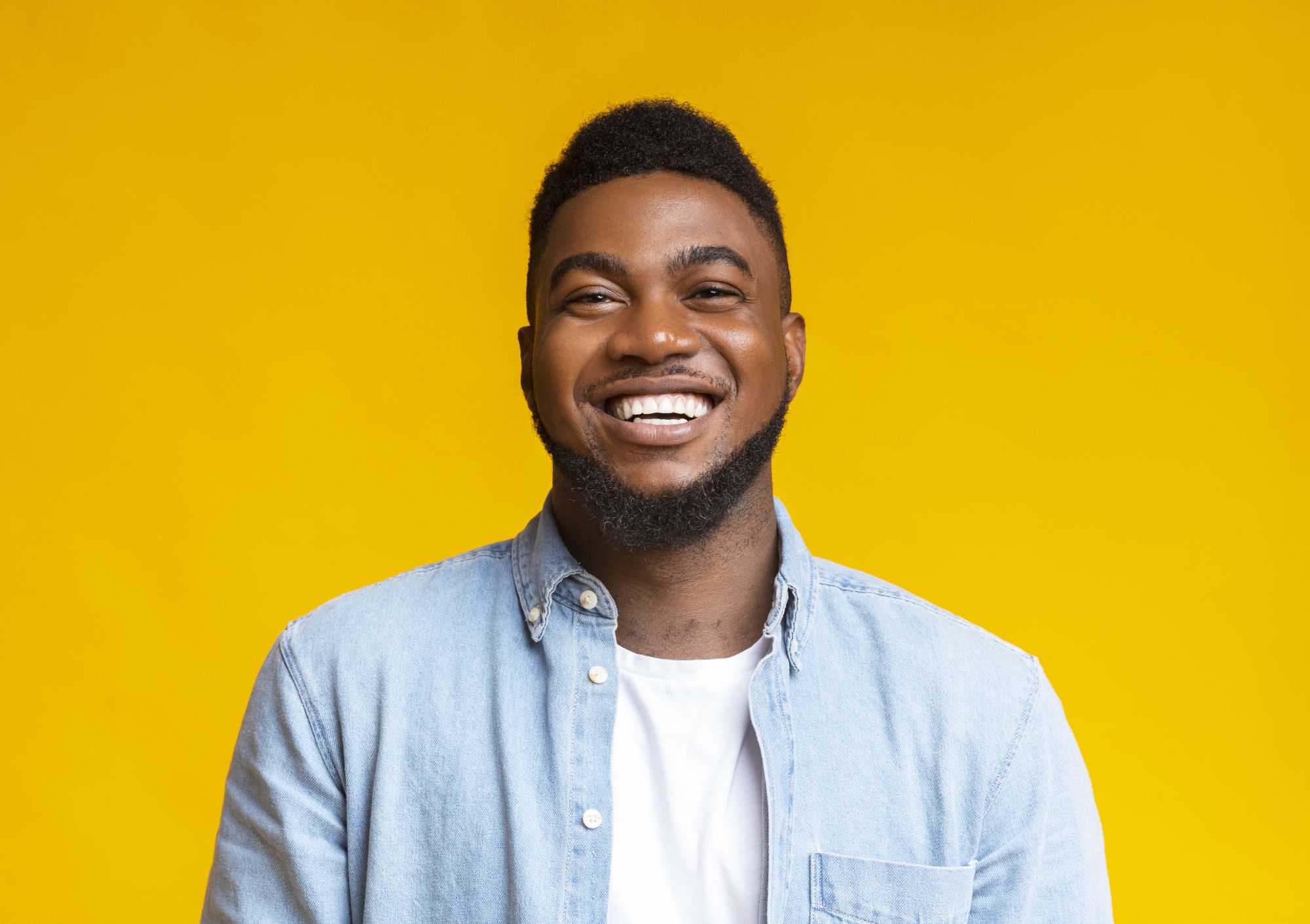 Smiling adult man in a denim shirt showing a straight, healthy smile from an adult orthodontist in Bartlett, TN