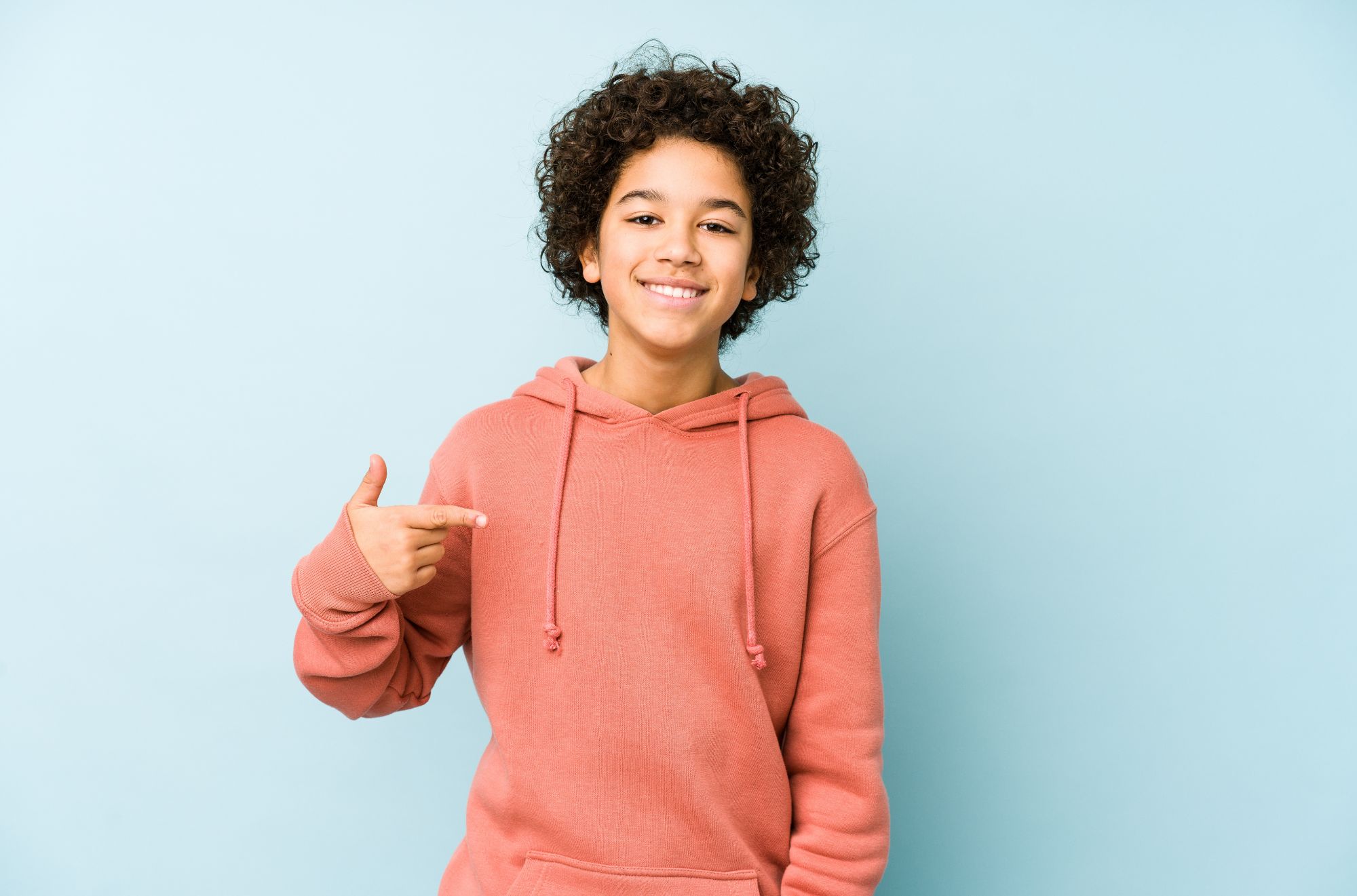 Smiling teen in a pink hoodie with a straight smile after orthodontic treatment in Bartlett, TN